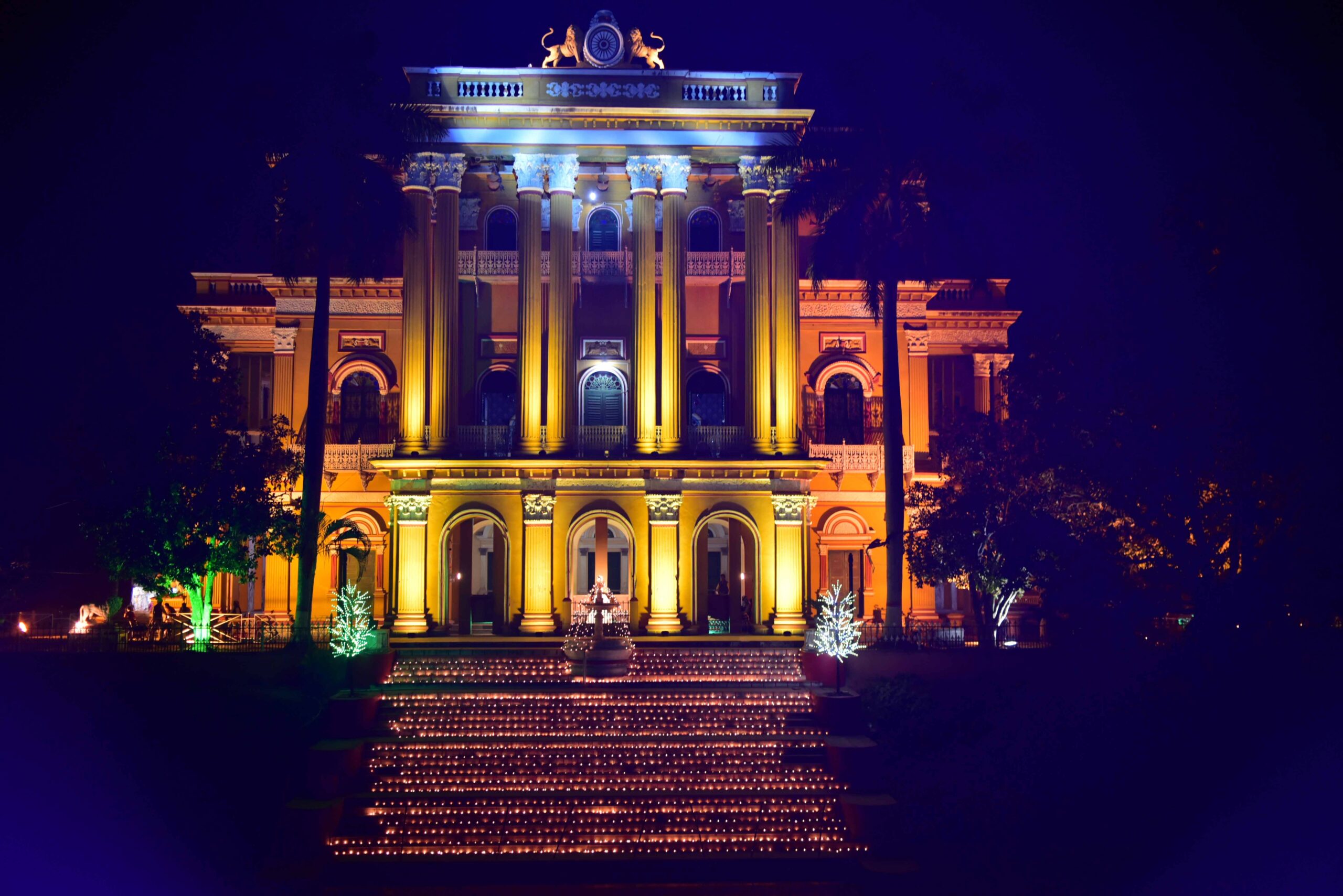 Exterior view of Grand Royal Kathgola Palace decorated with lights, candles, and a pond, an ideal heritage wedding venue linked to House of Sheherwali in Azimganj