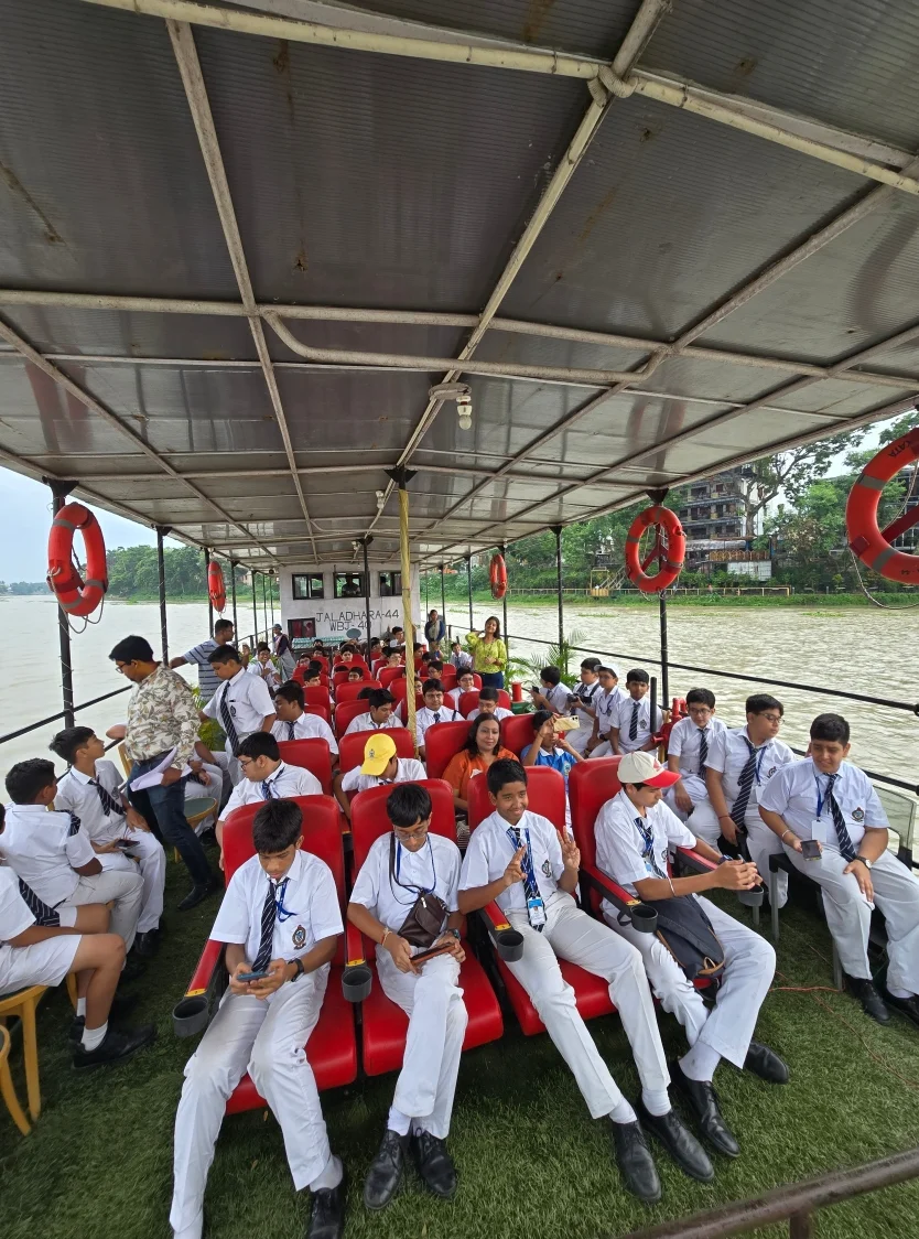 Uniformed school students seated aboard a covered boat during a Bhagirathi river excursion in Azimganj